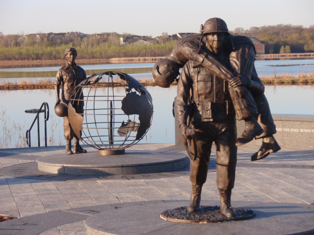 Bronze military memorial soldier carrying wounded soldier statue with female military nurse statue and world globe monument