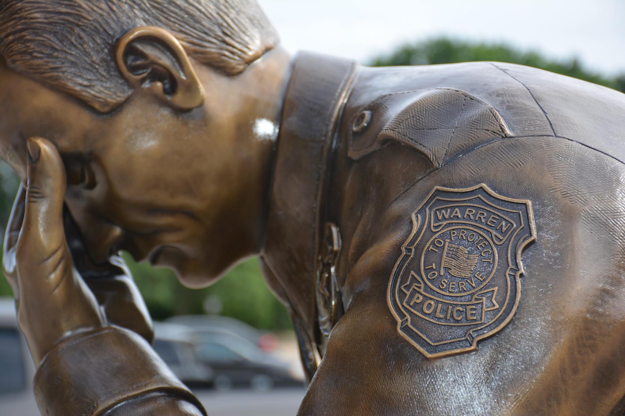 Close up of bronze kneeling police officer statue in uniform