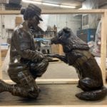 Bronze military memorial female soldier statue shaking paw of canine