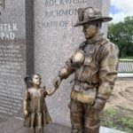 Bronze firefighter monument in uniform with equipment holding child statue