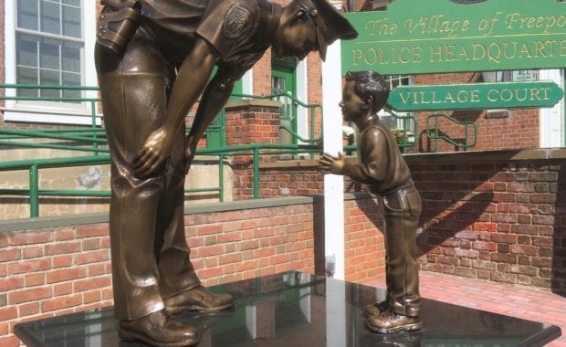 Bronze police officer statue bending down towards child