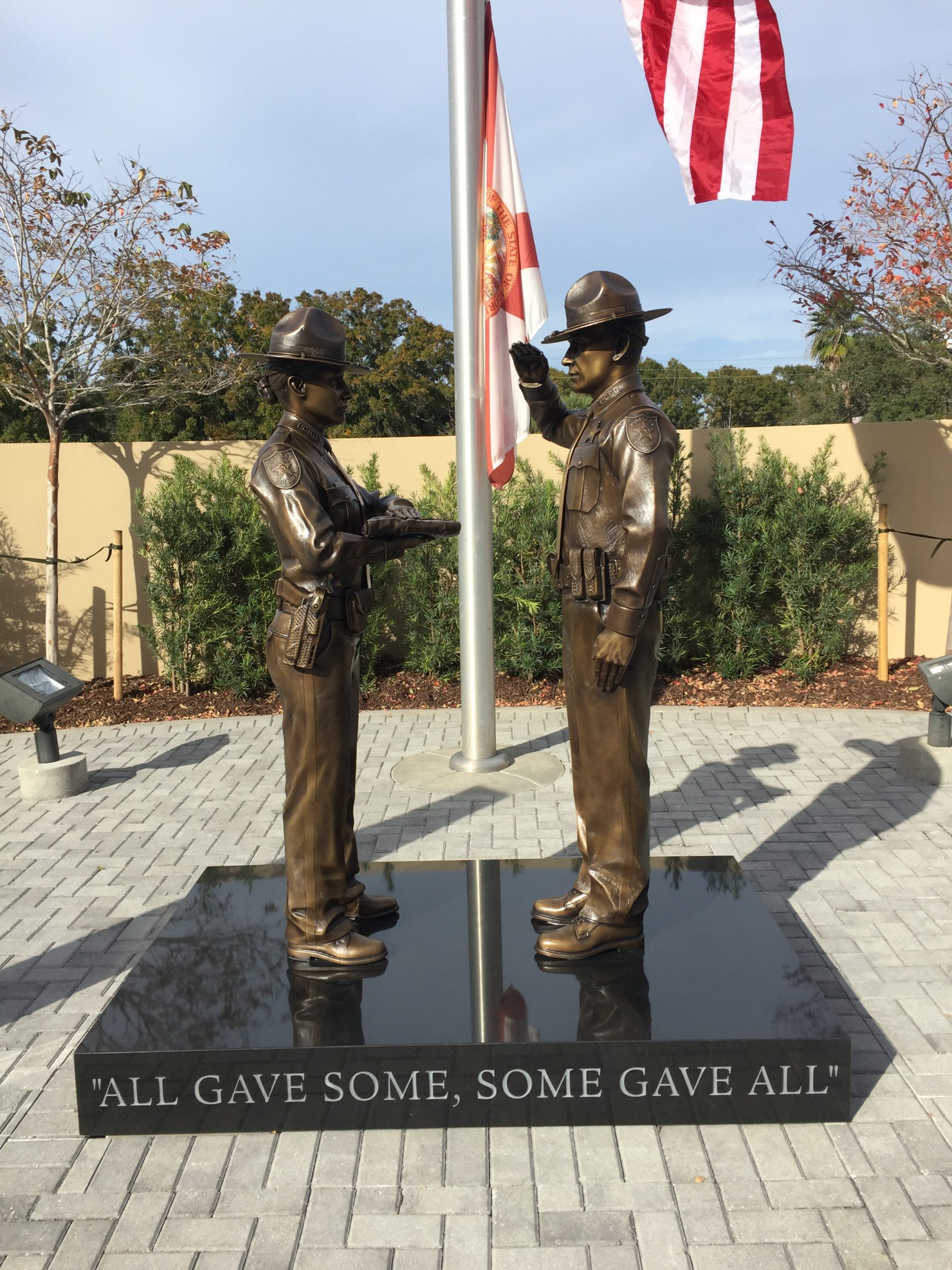 Bronze law enforcement honor guard statues: deputy presenting the flag and deputy saluting.