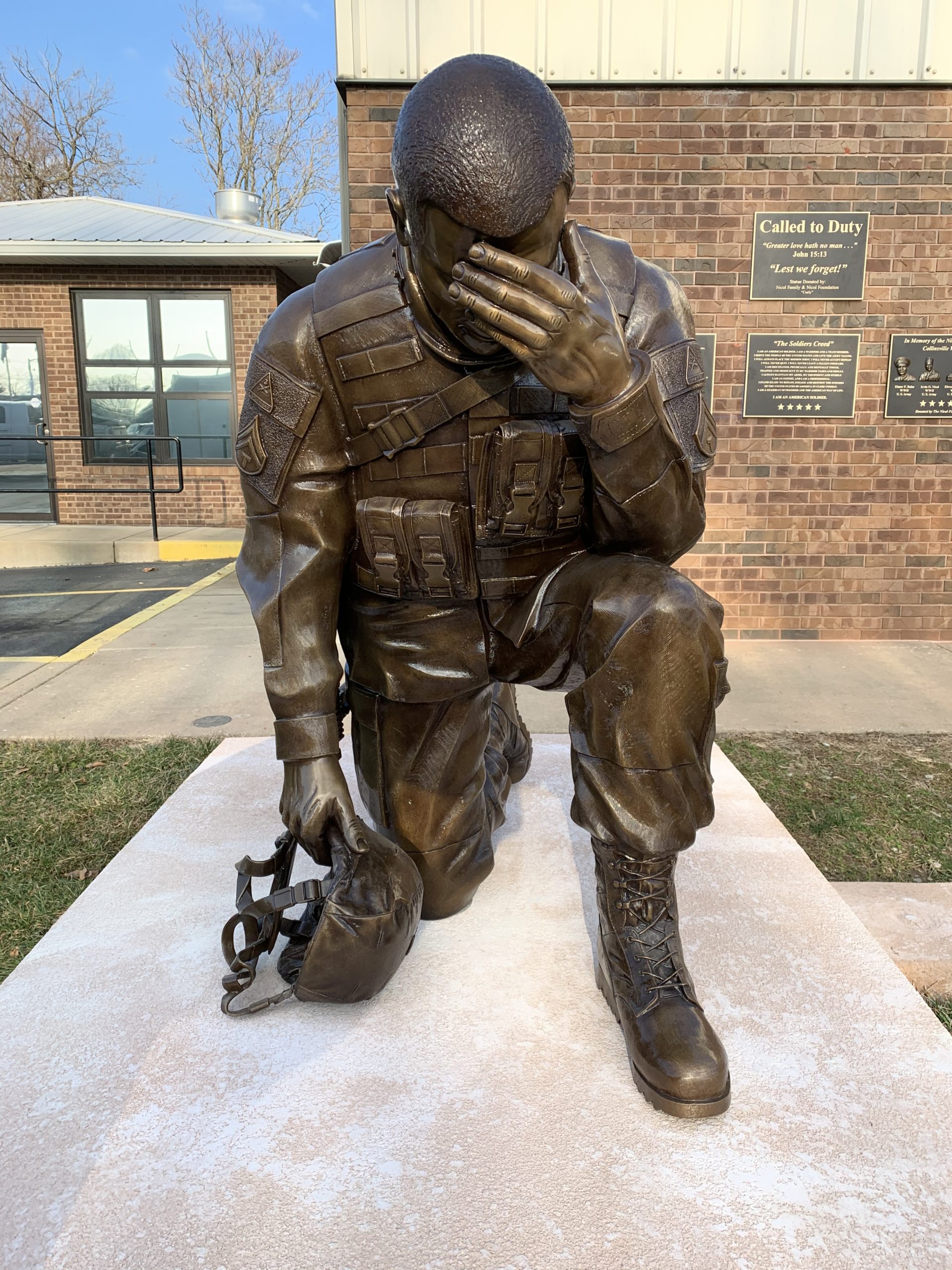 Bronze kneeling soldier statue in uniform military memorial