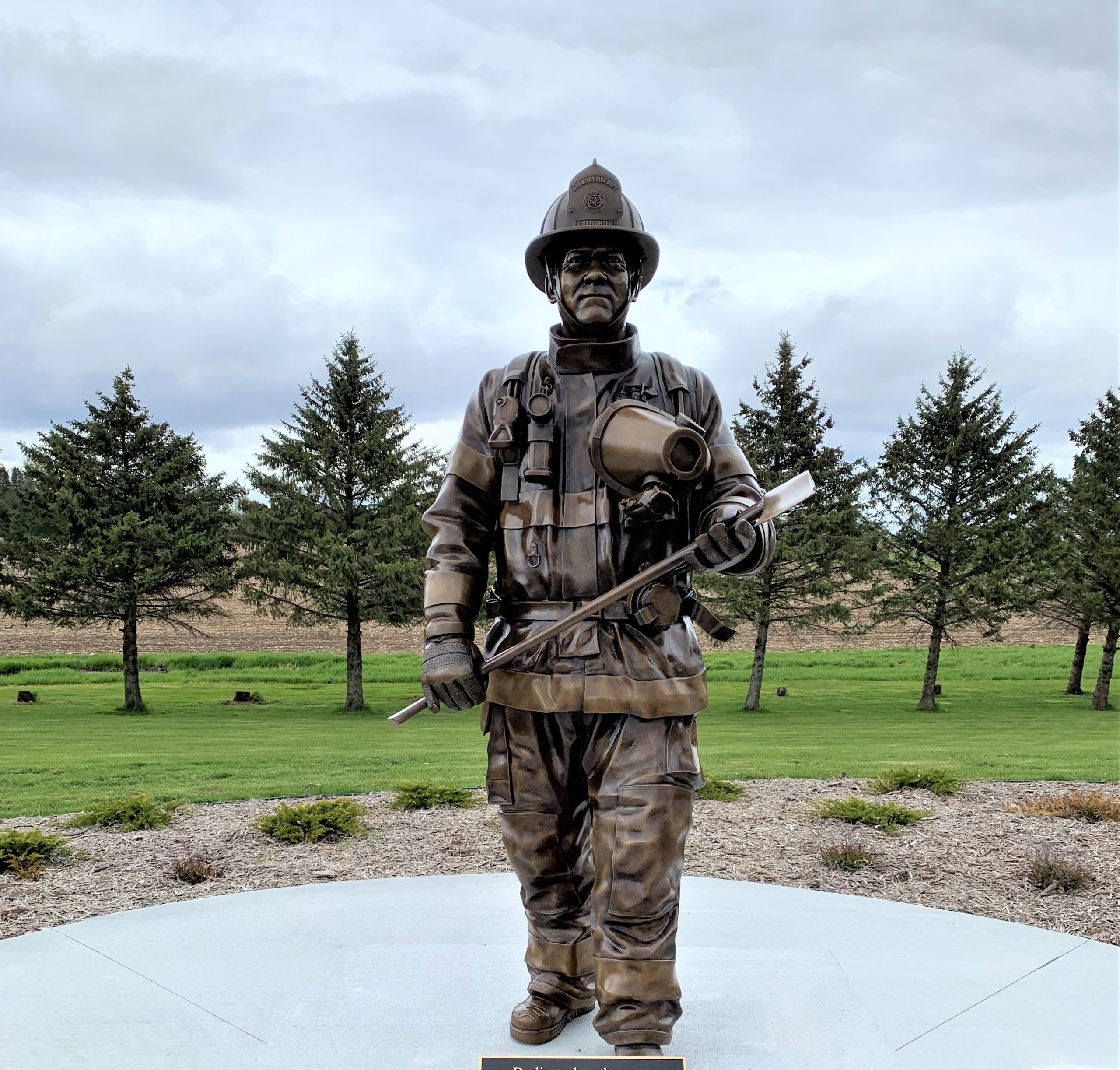 Bronze firefighter in uniform with gear holding axe statue