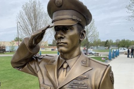 Bronze military memorial saluting soldier in dress uniform