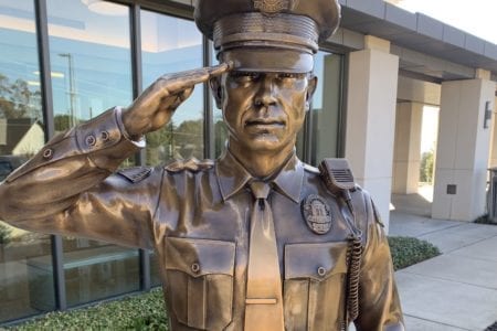 Bronze police officer in uniform saluting statue