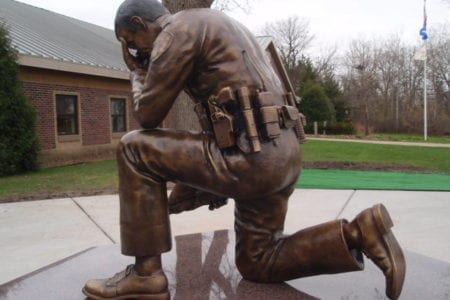 Bronze kneeling police officer statue in uniform