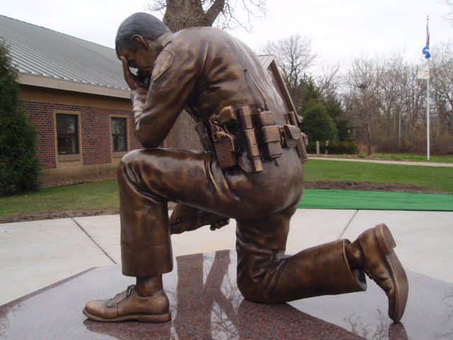 Bronze kneeling police officer statue in uniform