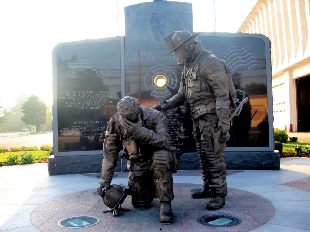 Bronze kneeling firefighter and standing firefighter in uniform statues