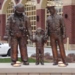 Bronze police officer and firefighter in uniform with child statues