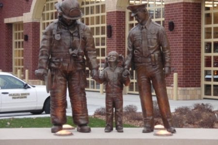 Bronze police officer and firefighter in uniform with child statues