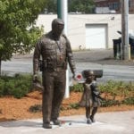 Bronze police officer in uniform walking with child statue
