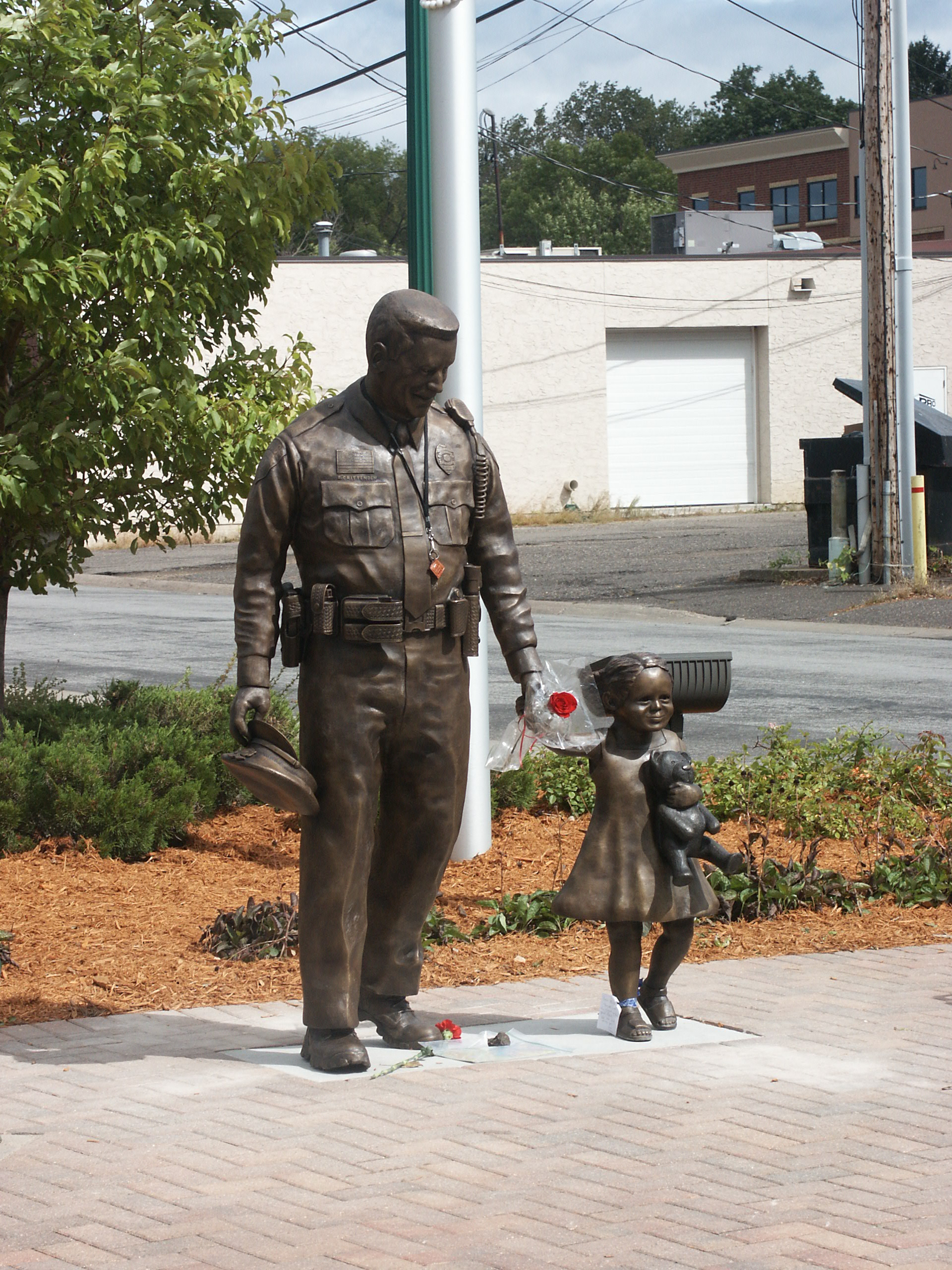 Bronze police officer in uniform walking with child statue